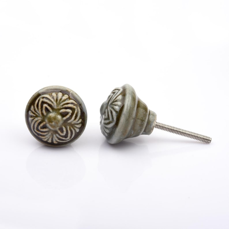May include: A collection of twelve decorative cabinet knobs in various colours and patterns. Each knob features a round or oval shape with a metal bolt extending from the back. The designs include floral, geometric, and solid textures in shades of green, blue, orange, purple, white, and grey.