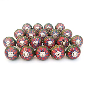 Peut inclure: Vingt boutons en céramique avec une base verte et un motif floral rouge et bleu. Chaque bouton a un centre en métal argenté.