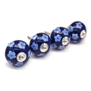 Puede incluir: Conjunto de cuatro pomos de armario de cerámica azul con un patrón floral azul claro. Cada pomo tiene una base de metal plateado.