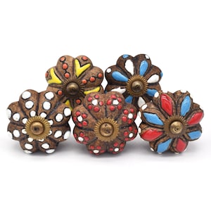 Op de afbeelding: Vijf keramische bloemvormige ladeknopjes met bruine bases en kleurrijke geschilderde ontwerpen. De knoppen hebben een messingkleurige schroef in het midden.