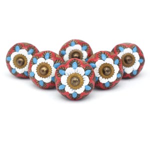 May include: Six red ceramic drawer knobs with white and blue floral designs. Each knob has a gold-coloured centre.
