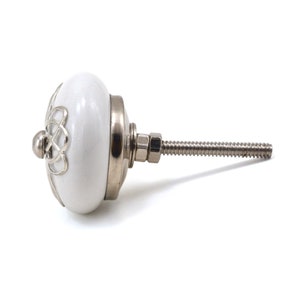 White ceramic cabinet knob with a silver flower motif and gold center; decorative furniture knob for cabinets and drawers.