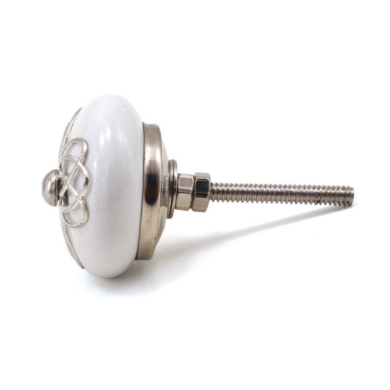 White ceramic cabinet knob with a silver flower motif and gold center; decorative furniture knob for cabinets and drawers.
