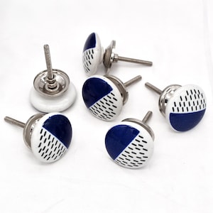 Peut inclure: Six boutons de porte en céramique blanche avec un motif géométrique bleu et blanc. Chaque bouton est doté d'une vis en métal argenté.