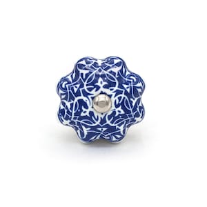 May include: A blue and white ceramic cabinet knob with a floral design. The knob has a silver-colored metal center and a scalloped edge. The decorative hardware is suitable for drawers and cabinets.