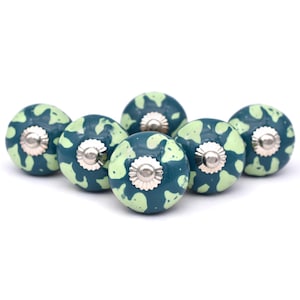 Könnte beinhalten: Sechs grüne und hellgrüne Keramik-Schrankknöpfe mit silbernem Metallakzent. Die Knöpfe haben ein gesprenkeltes Muster.