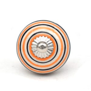 May include: A round ceramic knob with a silver center and orange and black stripes.