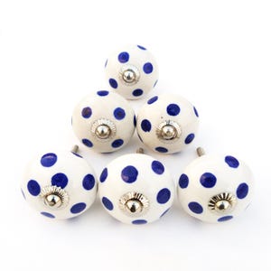 May include: Six white ceramic knobs with blue polka dots and silver accents.