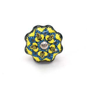 May include: A decorative cabinet knob with a floral design. The knob features a yellow background with blue and red accents. The knob is approximately 3.8 cm in diameter and has a silver metal center.