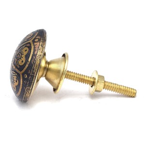 Etched brass flower cabinet knob with ornate gold pattern on dark background; decorative cabinet knobs for dresser hardware.
