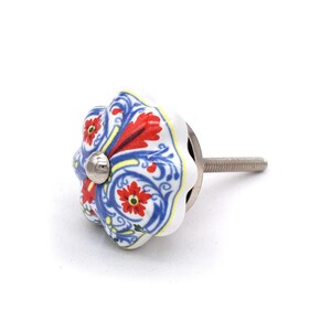 以下が含まれることがあります： 花柄デザインの装飾用セラミックキャビネットノブ。ノブは、赤、青、黄色の花柄模様の白いベースが特徴です。取り付け用のシルバーメタルネジが付いています。ノブの直径は約4cmです。