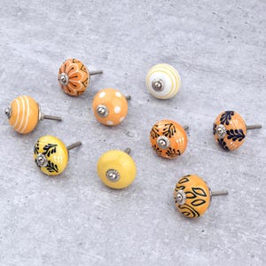 Hand-painted ceramic round knobs in yellow and orange with floral; dresser knobs and cabinet pulls for furniture hardware.