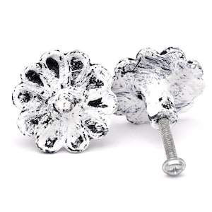 Könnte beinhalten: Zwei dekorative Schrankknöpfe in Blumenform, weiß lackiert mit schwarzen Akzenten. Jeder Knopf hat eine Metallschraube zur Befestigung. Diese Knöpfe sind für Möbel und Inneneinrichtung konzipiert. Durchmesser ca. 4 cm.