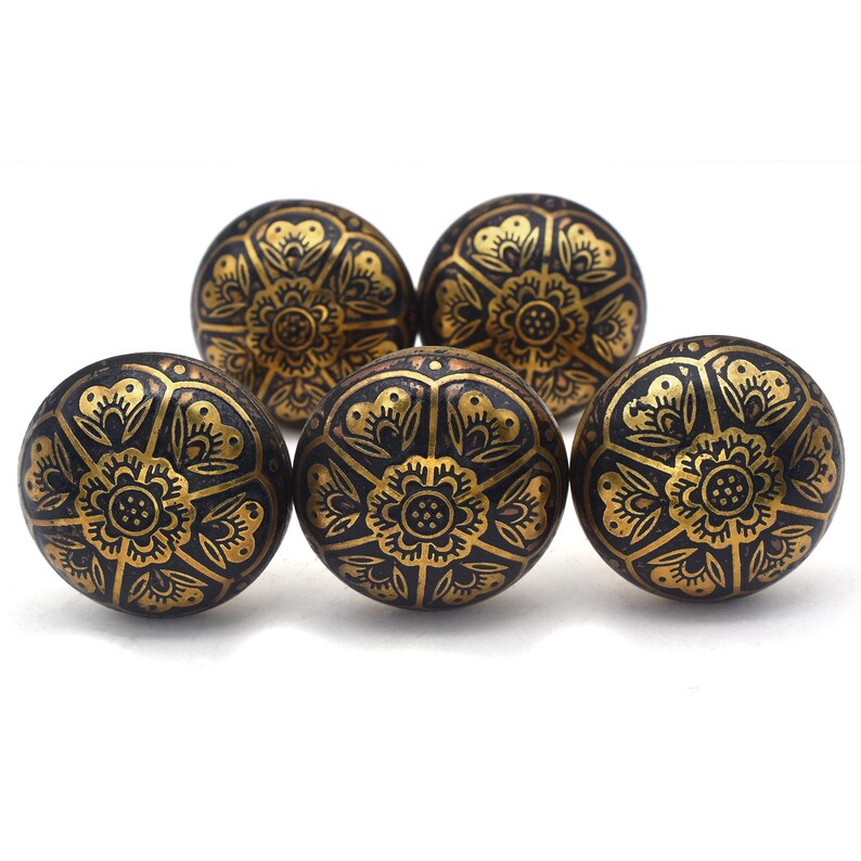 Etched brass flower cabinet knob with ornate gold pattern on dark background; decorative cabinet knobs for dresser hardware.