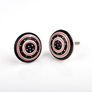 May include: A white ceramic mug with a black handle and the text "But First, Coffee" in a bold, black font. The mug is set against a blurred background, suggesting a cosy setting.