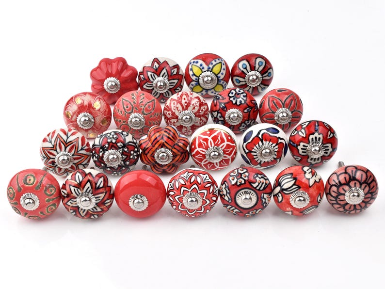 Red ceramic knobs with hand-painted white floral and mandala designs; assorted cabinet knobs for furniture and home décor.