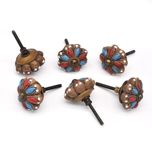 Puede incluir: Seis pomos de armario de cerámica con base marrón y diseño floral en tonos rojos, azules y blancos. Los pomos tienen un accesorio de tornillo de metal.