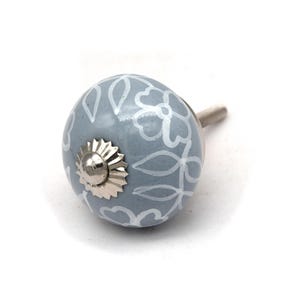 Grey ceramic knob with white hand-painted floral pattern; vintage shabby chic cabinet drawer pull with silver mounting stud.