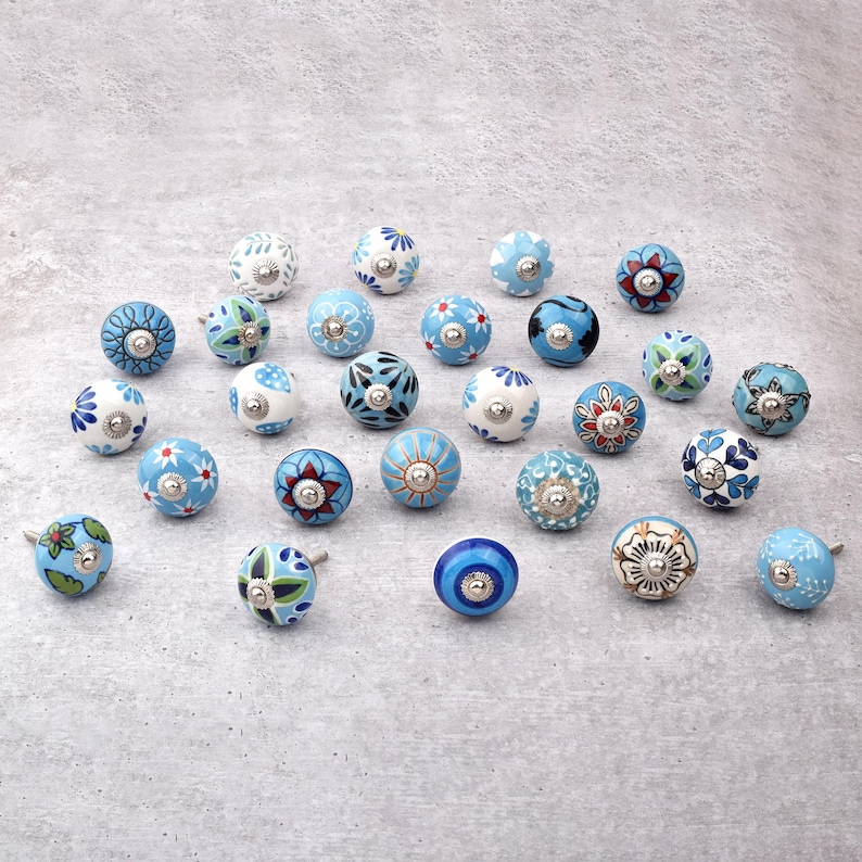Assorted hand-painted ceramic knobs with blue and turquoise floral motifs for kitchen décor and knob cupboards.