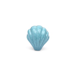 May include: A turquoise ceramic knob shaped like a seashell with a glossy finish and a distinct crackle glaze pattern. The object features a fan-like structure with vertical ridges radiating from the base to the rounded top edge.