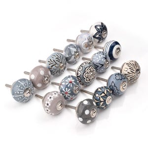 Assorted ceramic cabinet knobs, handpainted in blue, gray, and white with mandala and floral patterns for cabinet hardware.
