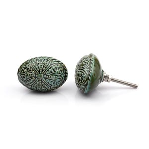 May include: A collection of twelve decorative cabinet knobs in various colours and patterns. Each knob features a round or oval shape with a metal bolt extending from the back. The designs include floral, geometric, and solid textures in shades of green, blue, orange, purple, white, and grey.