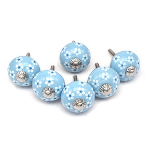Six sky-blue ceramic cabinet knobs with white dotted floral patterns; hand-painted dresser and drawer knobs with metal screw posts.
