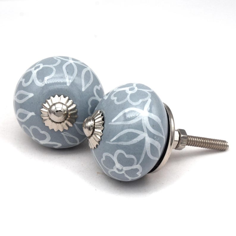 Grey ceramic knob with white hand-painted floral pattern; vintage shabby chic cabinet drawer pull with silver mounting stud.