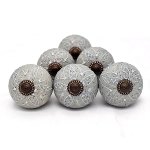 Peut inclure: Six boutons de porte en céramique gris avec des motifs floraux blancs et des accents bronze.