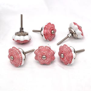 Peut inclure: Six boutons de meubles décoratifs. Chaque bouton présente une base blanche ornée d'un motif floral rouge détaillé. Ils sont dotés de vis en métal argenté et d'un petit centre rond. Parfaits pour les meubles et la décoration intérieure.