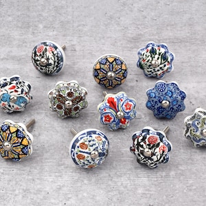 May include: Assortment of 10 ceramic drawer knobs with colourful floral and geometric patterns. The knobs are white with a silver metal screw.