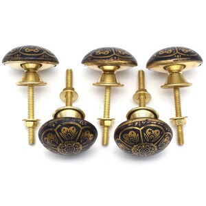 Etched brass flower cabinet knob with ornate gold pattern on dark background; decorative cabinet knobs for dresser hardware.