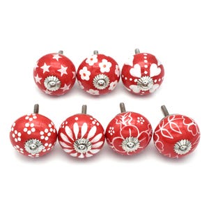 Peut inclure: Ensemble de huit boutons de cabinet en céramique rouge avec des motifs floraux et géométriques blancs.