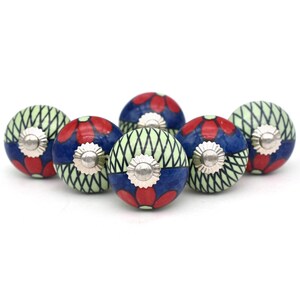 May include: A set of six decorative ceramic cabinet knobs. Each knob features a blue and red floral design, with a silver-colored metal base. The knobs have a light green and white crisscross pattern on the sides.