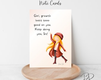 May include: Note card with the text "Girl, growth looks sooo good on you. Keep doing you, Sis!" and an illustration of a girl in a red coat and hat. The card is on a wooden tray.
