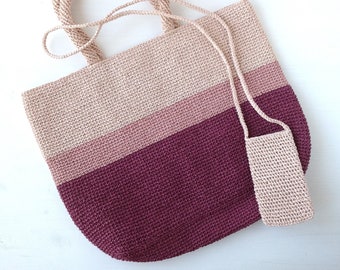 May include: A crocheted tote bag with a pink and burgundy striped design. The bag has a long strap and a smaller matching pouch.