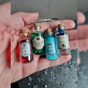 May include: Four small glass bottles with cork stoppers and labels. The bottles contain different colored liquids and have labels that read "Elixir of Life", "Shape-shifting Potion", "Peace Potion", and "Werewolf Potion".