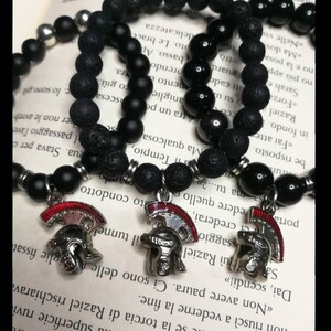 May include: Three black beaded bracelets with silver accents and Roman helmet charms. The bracelets are made of black lava rock and onyx beads.