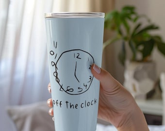 Può includere: Un bicchiere azzurro con un disegno di orologio nero disegnato a mano e le parole "off the clock". Il bicchiere ha un coperchio argentato. Il disegno dell'orologio include i numeri 12, 2, 3, 4, 5 e 11.
