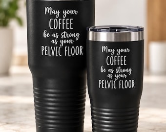 May include: Two black stainless steel tumblers with clear lids, featuring the white printed text: May your COFFEE be as strong as your PELVIC FLOOR. The tumblers have a textured, ribbed base and a smooth upper section, standing upright side by side.