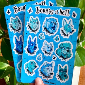 May include: Two blue sticker sheets with various dog illustrations wearing spiked collars. The text "Hounds of Hell" is at the top of each sheet. The stickers are on a blue grid background.