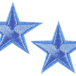 May include: Two embroidered blue star patches. Each star features a five-pointed design with a lighter blue fill and a darker blue outline. These patches are likely for decorative use on clothing or accessories.