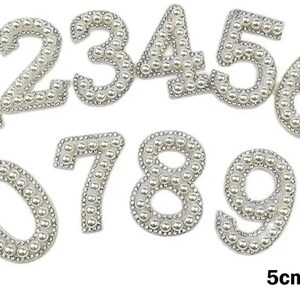 May include: A set of pearl-embellished numbers, 0 to 9, each about 5 cm tall. The numbers are edged with tiny, clear rhinestones. The text "5cm Tall" is displayed in the bottom right corner.