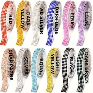 May include: Twelve rolls of adhesive rhinestone ribbon in various colours including red, dark yellow, AB silver, dark blue, pink, lilac, champagne, silver, aqua, light yellow, black, and dark green, each labelled with its respective colour name.