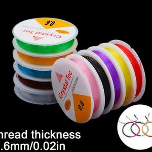 May include: A selection of colourful elastic beading cord spools, with colours such as green, orange, blue, pink, black, purple, yellow, and red. The spools are labelled "Crystal Tec" and "0.6". The thread thickness is 0.6mm/0.02in. Some finished bracelets are also shown.