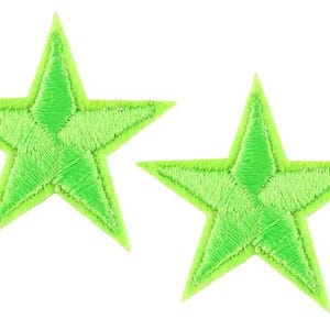 May include: Two lime green embroidered star patches. Each star features a five-point design with a lighter green outline and a textured, stitched appearance. The patches are set against a white background.