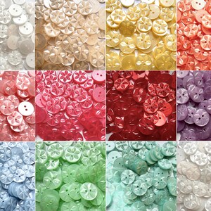 May include: A collection of round buttons in twelve distinct colours, each featuring a moulded six-petal flower design and two central holes for attachment, arranged in a grid of individual colour-themed groupings.