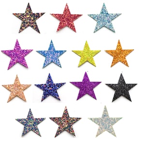 May include: A selection of glittery star-shaped embellishments in various colours, including black, blue, green, orange, pink, purple, and gold. The stars are arranged on a white background, showcasing their sparkly texture and vibrant hues. These decorative stars are ideal for crafts.