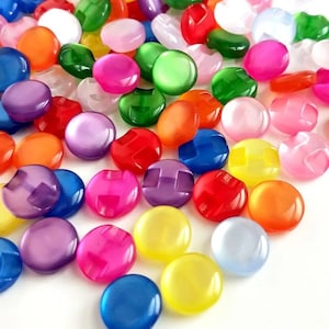 May include: A selection of vibrant, round buttons in shades of pink, green, orange, blue, purple, and yellow. The buttons have a glossy finish and a two-hole design, suitable for sewing or craft projects.