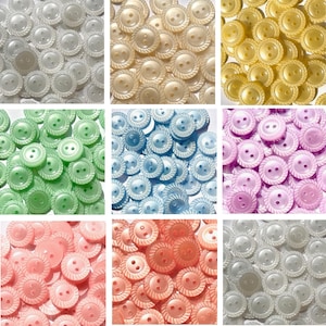 May include: A selection of colourful, round buttons in shades of white, yellow, green, blue, pink, and coral. Each button features a decorative rope-like edge and two holes for sewing. These buttons are suitable for sewing and craft projects.